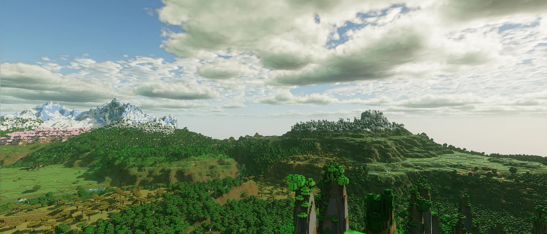 Rolling green hills and forest under a bright sky, with snowy peaks on the horizon.