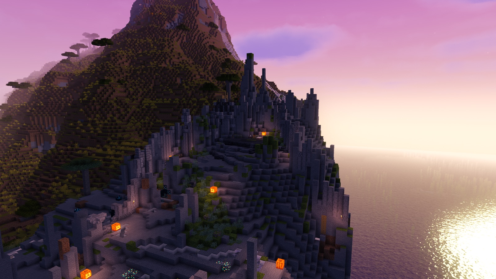 A stone-terraced build climbing a coastal mountain on the Valor SMP world at sunset, ocean to the right.